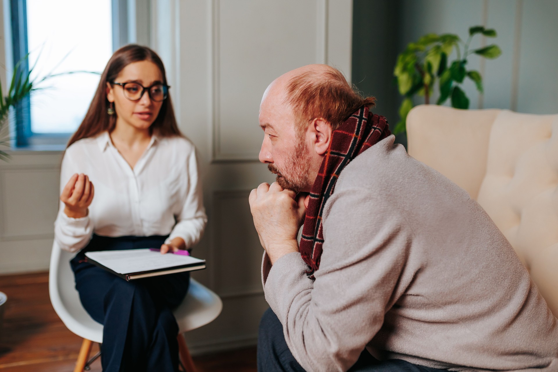 Hombre en discusión reflexiva con un terapeuta en un entorno de oficina moderno