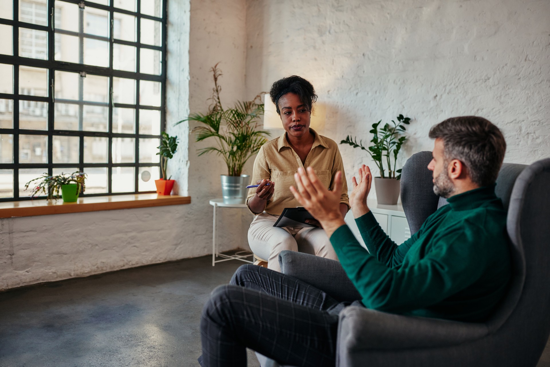 Terapeuta femenina africana escucha a cliente masculino adulto medio