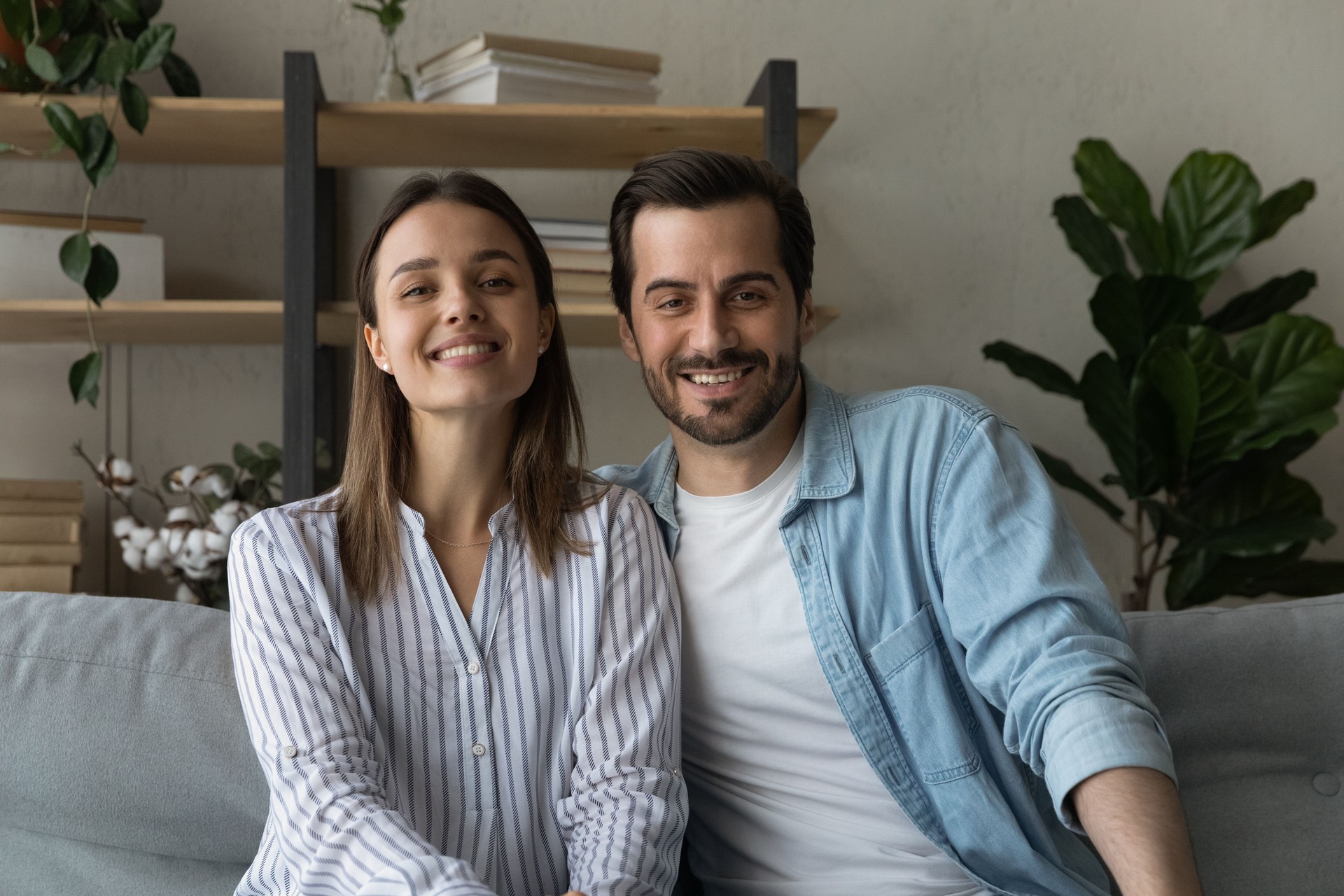 Hermosa pareja casada sentarse en el sofá sonrisa mirar a la cámara