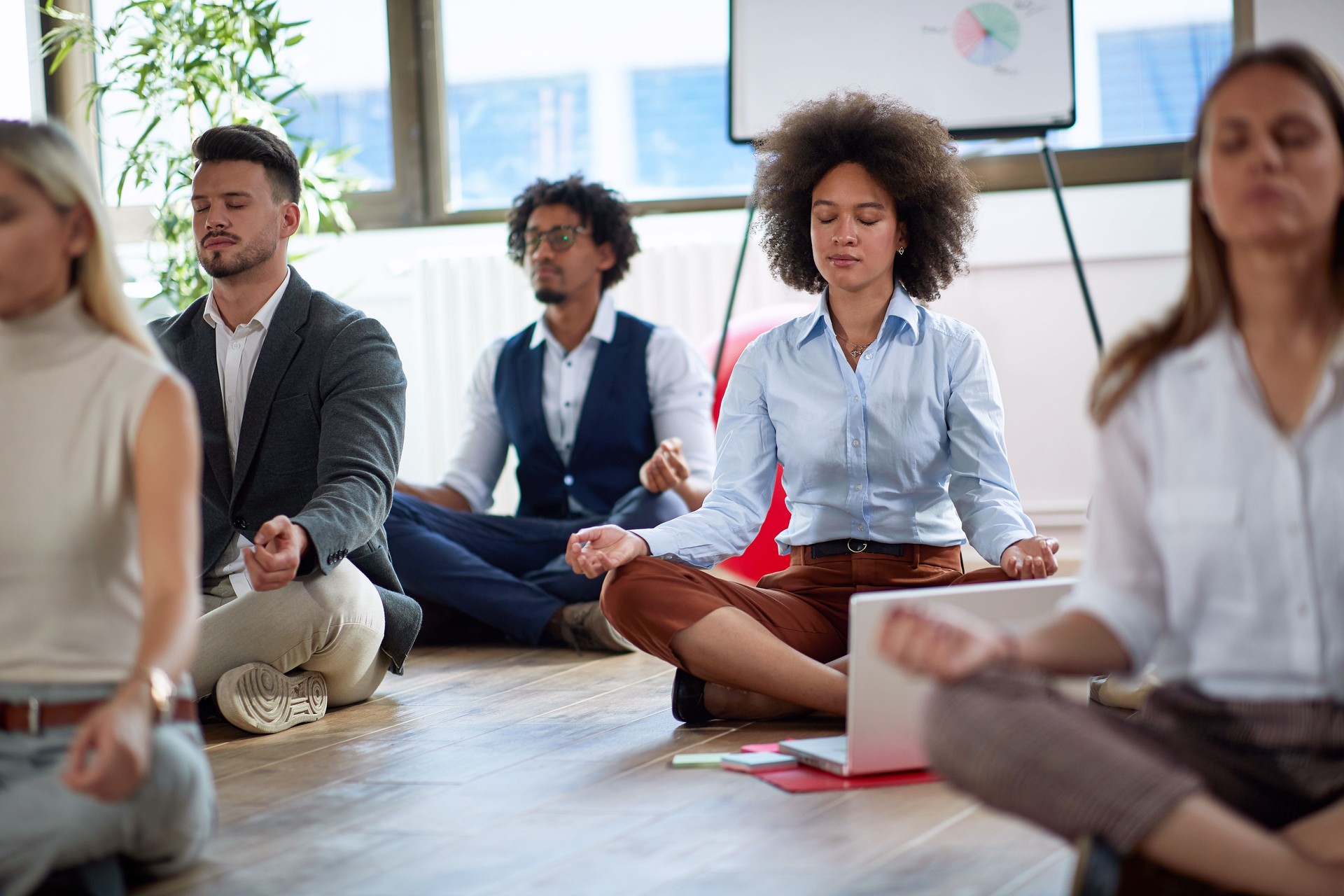 Empleados de oficina tomando un descanso para hacer una meditación. Compañeros de trabajo meditando en el suelo.