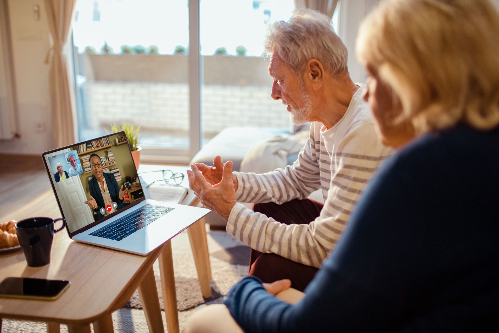 Pareja de ancianos hablando con su consejero a través de una videollamada